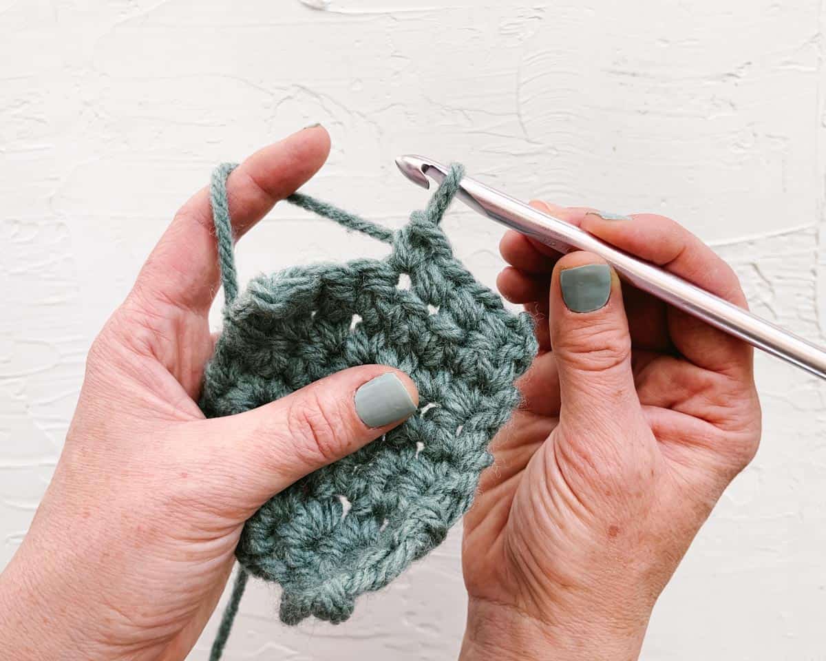 Demonstration of crochet pencil grip using wooden crochet hook and green yarn.
