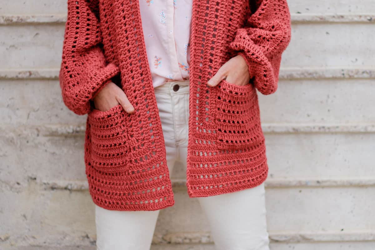 Woman's torso with her hands in the pockets of the easy crochet hexagon cardi she's wearing. 