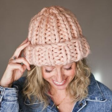 Pink chunky knit hat modeled by a blond woman.