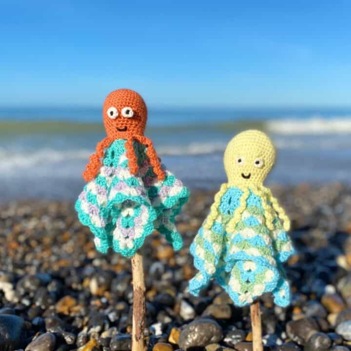 Two octopus baby comforters on sticks on the beach.