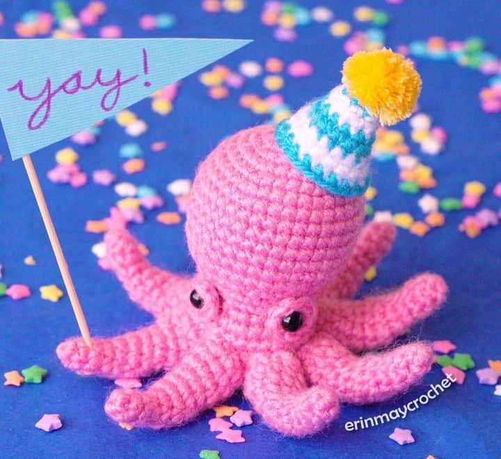 A pink octopus with a party hat and a banner that says yay!