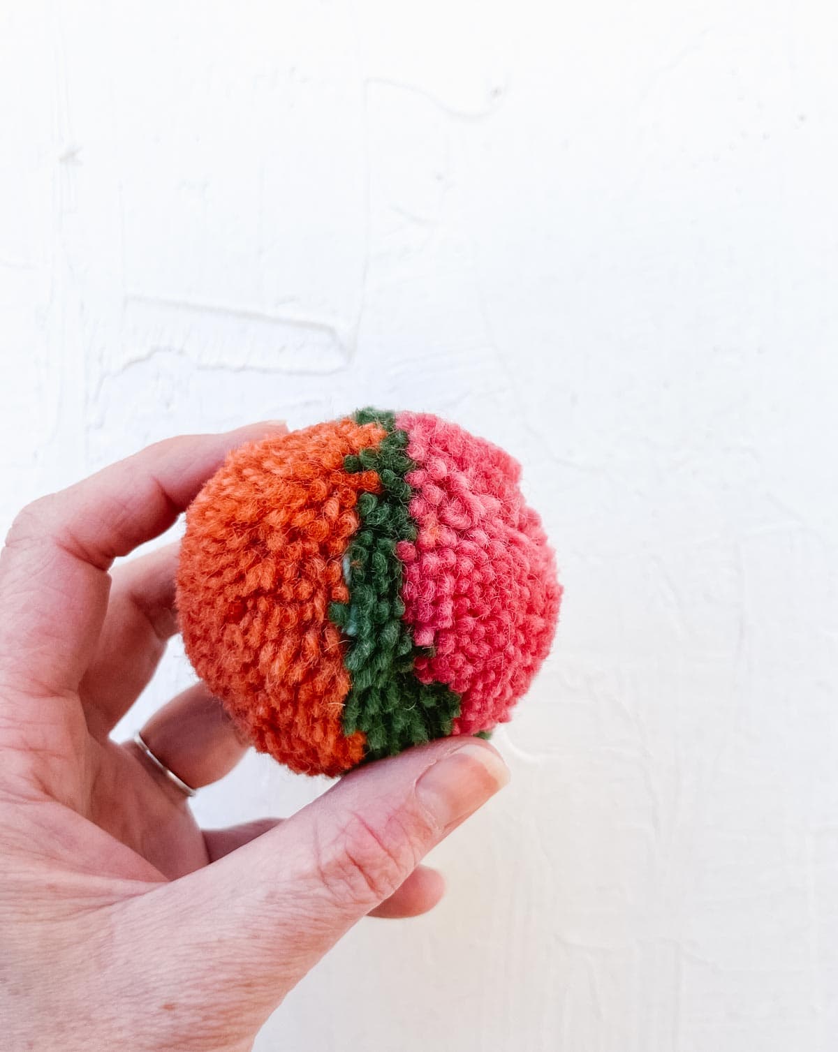 A DIY pom pom made with three colors of yarn.