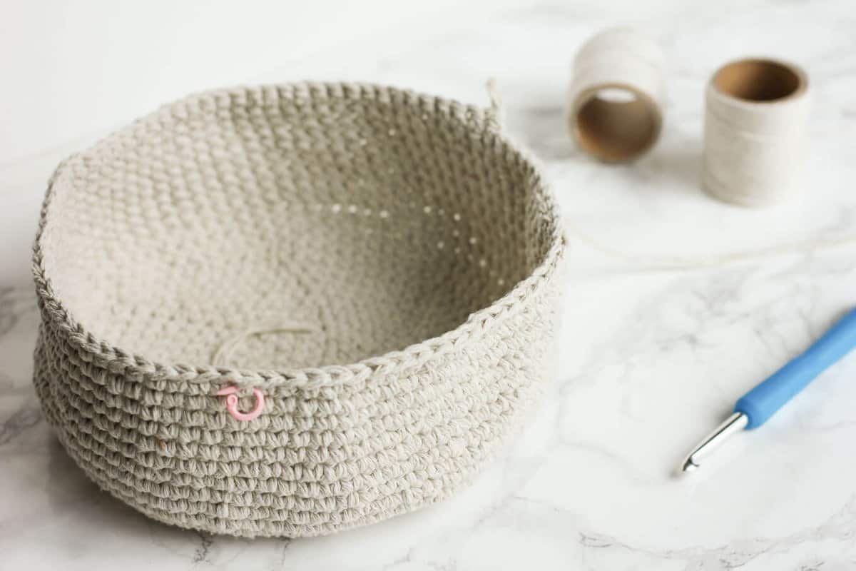 An crochet basket that is being made in the round with single crochet stitches.